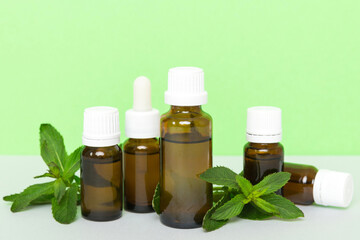 Natural Mint Essential Oil in a Glass Bottle. organic cosmetics with herbal extracts of mint on colored background