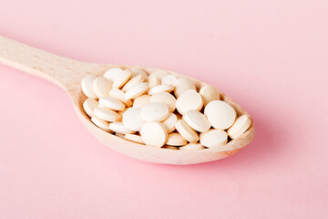 Heap of white pills on colored background. Tablets scattered on a table. Pile of red soft gelatin...