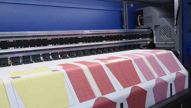 a digital textile printer in printing colorful shirt patterns directly onto fabric rolls.