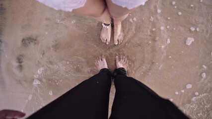 Feet of a couple standing close on wet beach sand as ocean waves gently touch their feet, symbolizing beach fashion, travel moments, connection, and relaxed coastal lifestyle - Powered by Adobe