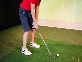 Golfer practicing swing technique indoors at a virtual golf simulator