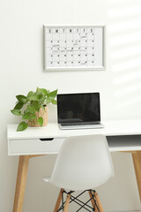 modern office workplace desk with laptop and financial diagrams, against flipchart on wall time...