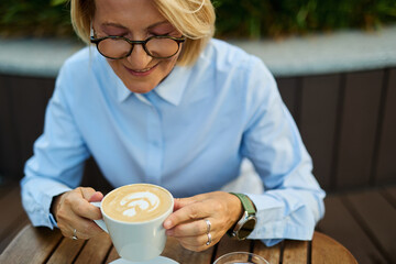 Portrait of a middle aged mature businesswoman woman drinking a cappuccino in a coffee shop