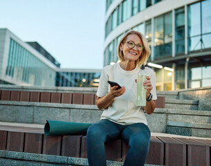 Portrait of a middle aged mature  beautiful sport woman smiling happy and talking at smartphone...