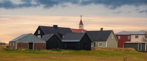 Small village with historic church in Eyrarbakki, in rural southern Iceland with cloudy skies.