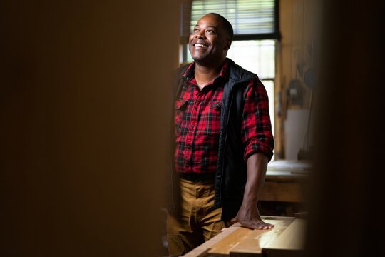 Portrait of a smiling african american carpenter in his woodshop looking up happy