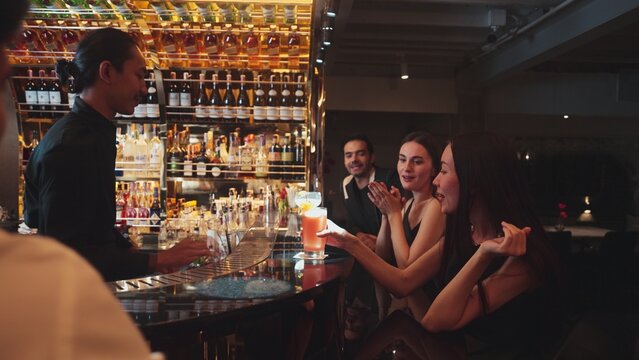 Beautiful woman with Paloma cocktail drinks smoothy making cheers with friend holding Margarita glass refreshing beverage at luxurious counter bar friendship and couple meeting at nightclub. Vinosity.