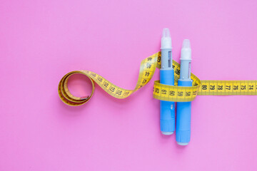 Insulin pens wrapped in a measuring tape on a pink surface, illustrating healthcare, weight management, and chronic illness support. drugs injection ozempic for weight loss