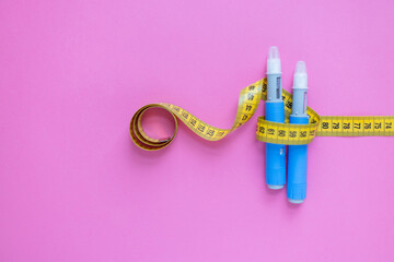 Concept image of diabetes and obesity treatment with two insulin pens and a measuring tape on pastel background. drugs injection ozempic for weight loss