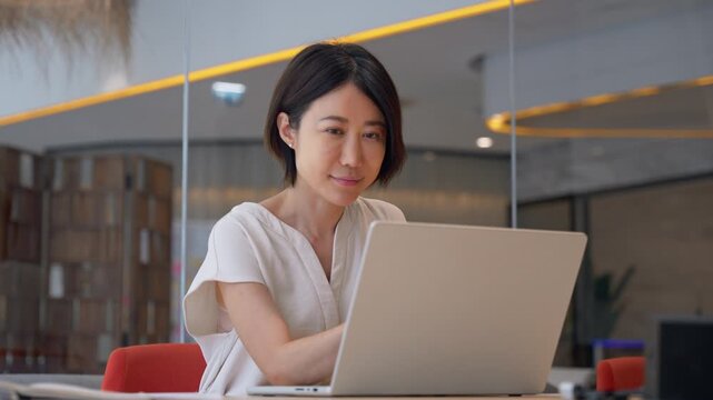 Asian entrepreneur manager businesswoman finance analyst using pc for data analysing at workplace. Focused mature eastern business woman working on laptop computer sitting at office workplace desk