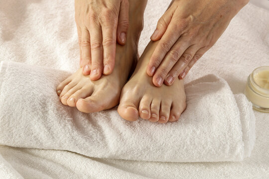 Woman gently massaging sore feet and ankle, focusing on pain relief and relaxation, muscle fatigue, cramps or swollen feet after long day, personal care, wellness, therapeutic massage, healing at home - Powered by Adobe