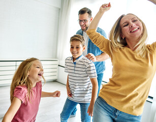 Portrait of a three generation famili, grandparents, parents and children playing and having fun dancing at home