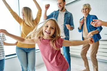 Portrait of a three generation famili, grandparents, parents and children playing and having fun dancing at home