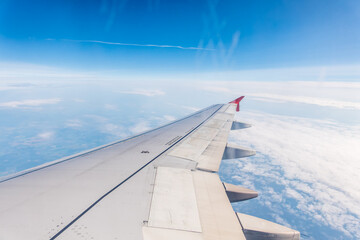 View from the airplane window at a beautiful cloudy sky and the airplane wing