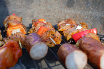 Grilled meat skewers and sausages cooking on a charcoal barbecue.