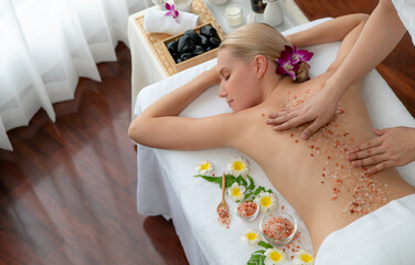 Woman customer having exfoliation treatment in luxury spa salon with warmth candle light ambient....