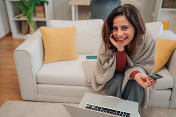 Happy woman shopping online using laptop and credit card at home