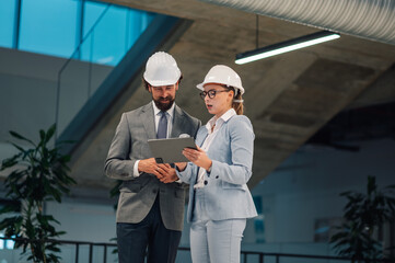 Architects using digital tablet discussing blueprint in modern building