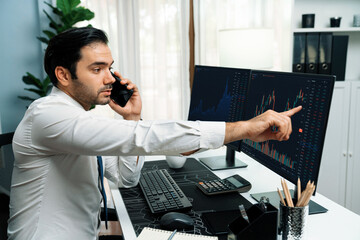 Trader businessman calling to consultant or partner with two stock exchange investment, compare...