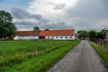 Fototapeta premium Road through farmland at the Flemish countryside in Dudzele Bruges, West Flanders, Belgium