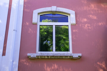 Window with white frame on a pink building exterior with decorative trim.