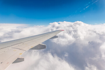 View from the airplane window at a beautiful cloudy sky and the airplane wing