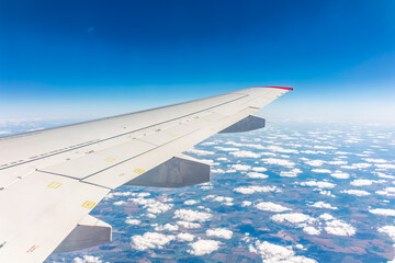 View from the airplane window at a beautiful cloudy sky and the airplane wing