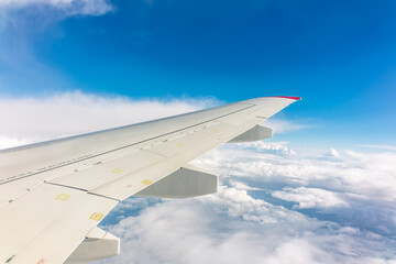 View from the airplane window at a beautiful cloudy sky and the airplane wing