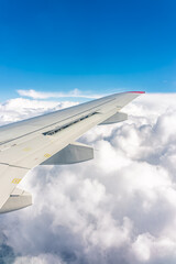 View from the airplane window at a beautiful cloudy sky and the airplane wing