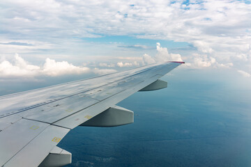 Obraz premium View of airplane wing, blue skies and green land during landing. Airplane window view.