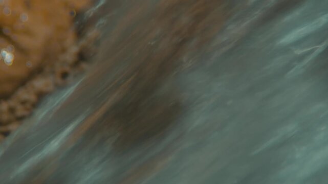 A dynamic long-exposure capture of a natural water surface with smooth movement, representing the motion of a wide river or stream in slow shutter speed. The image is abstract and flowing