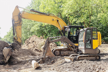 Yellow excavator on construction site. Heavy machinery working with soil. Digger machine during...