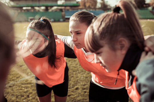 Teen soccer team huddling before match on outdoor field