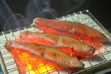 煙りの立ち昇る七輪で鮭を焼く