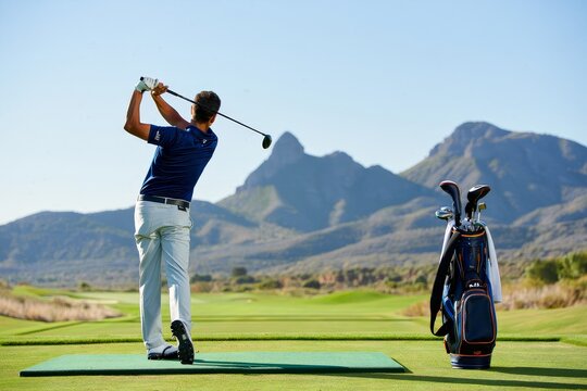 Golfer Swinging Driver on Tee Box with Mountain Backdrop
