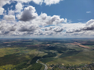 Scenic drone shot of green meadows, river curves, and village streets framed by a clear blue sky...