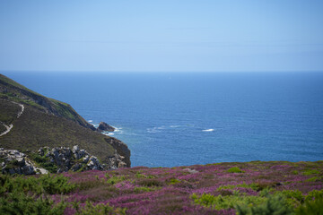 A dramatic view of a winding road along a steep coastal cliff in Brittany, France, with the sea far...