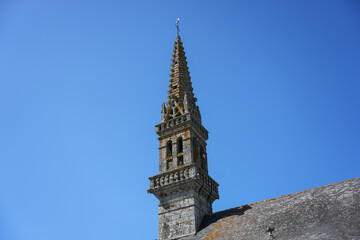 A low-angle, close-up view of a historic Breton gothic spire, showing the intricate stone...
