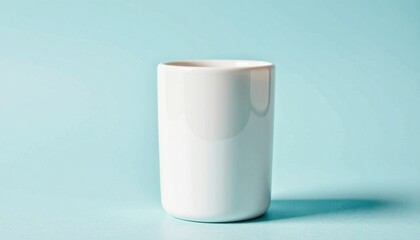 A clean and modern white ceramic tumbler shown in a minimalist composition, a versatile container for drinks or decor against a calm pastel blue background.