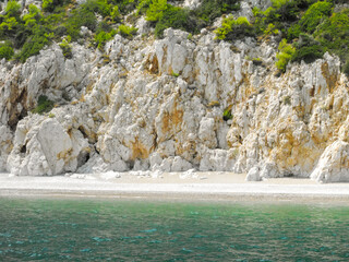 A rocky shoreline with a green beach and a blue ocean