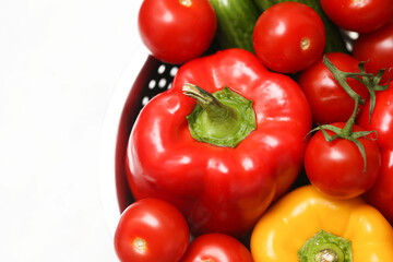 Fresh organic vegetables closeup. Red bell pepper with tomatoes and cucumber in bowl. Healthy cooking ingredients. Colorful harvest from garden. Natural vegan food concept. Isolated on white.