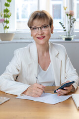 Portrait of business woman. Confident mature woman using mobile phone and typing. Vertical photo. High quality photo