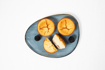 Homemade healthy muffins with blackberries on a ceramic plate on white background