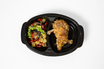Stewed chicken in sauce with braised vegetables on a plate on white background