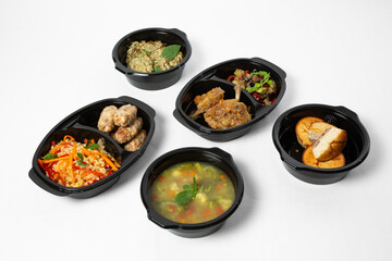 Set of healthy ready-made meals in black containers on a white background