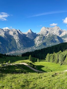 View from Citt&agrave; di Carpi Hut &ndash; Impressive Mountain Range Rising Above Lush Green Pine Forests under a Cloudy Sky, Dramatic and Majestic Landscape in the Dolomites, Italian Alps