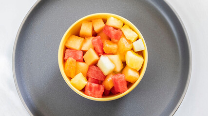 Top view of a small cup full of fruits on cubes.