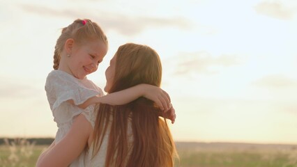Child girl hugging her mother in summer park in sun. Mom kid play together in sunny day. Happy...
