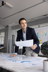 Man reviewing printed financial charts, evaluate business performance metrics, prepares for corporate presentation, analyze data for strategic insights or organizing project documentation in boardroom