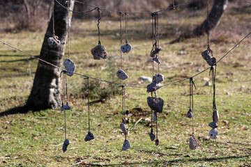 Irregular limestone rocks strung with string hang as a rustic wind chime, suspended between wires...